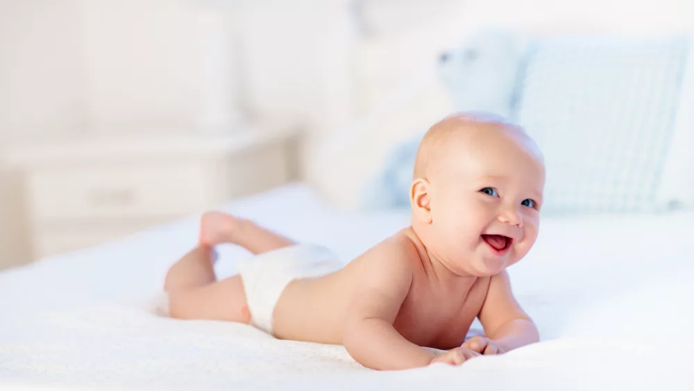 babyboywearingdiaperinwhitesunnybedroom-newbornchild