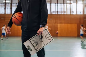 closeupofbasketballtrainershandsholdingballandclipboard