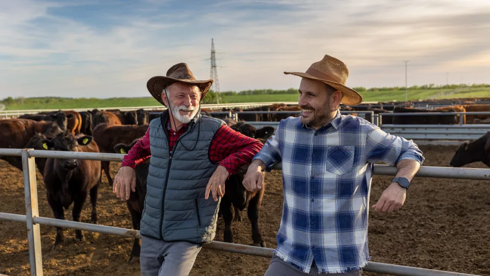 twosatisfiedfarmersfatherandsonleaningonfenceof
