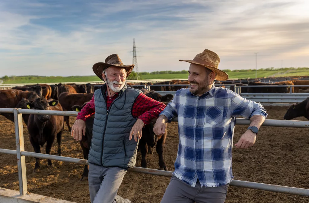 twosatisfiedfarmersfatherandsonleaningonfenceof