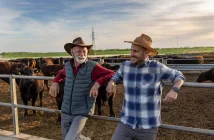 twosatisfiedfarmersfatherandsonleaningonfenceof