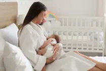 beautifulyounghappywomaninbathrobebreastfeedingherbabyat