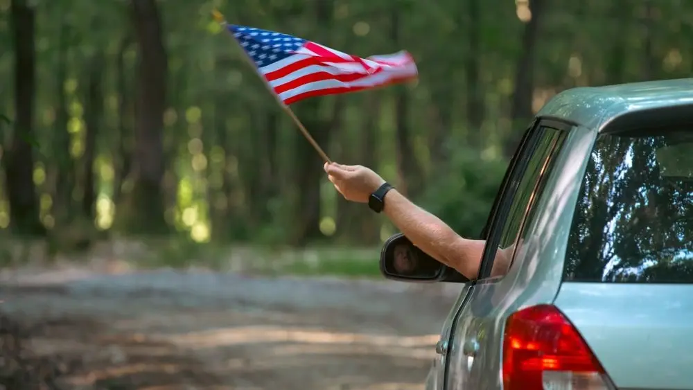 maninthecarholdingamericanusaflaginthe