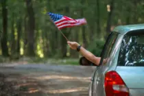 maninthecarholdingamericanusaflaginthe
