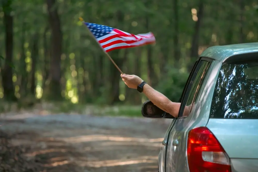 maninthecarholdingamericanusaflaginthe