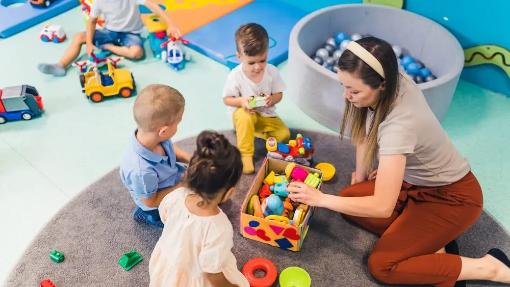 youngcaucasianteachersittingwithherkidsandplayingwith