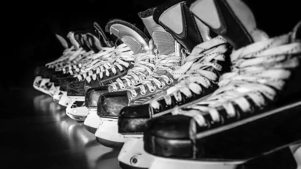 Pairs of hockey skates lined up in a locker room