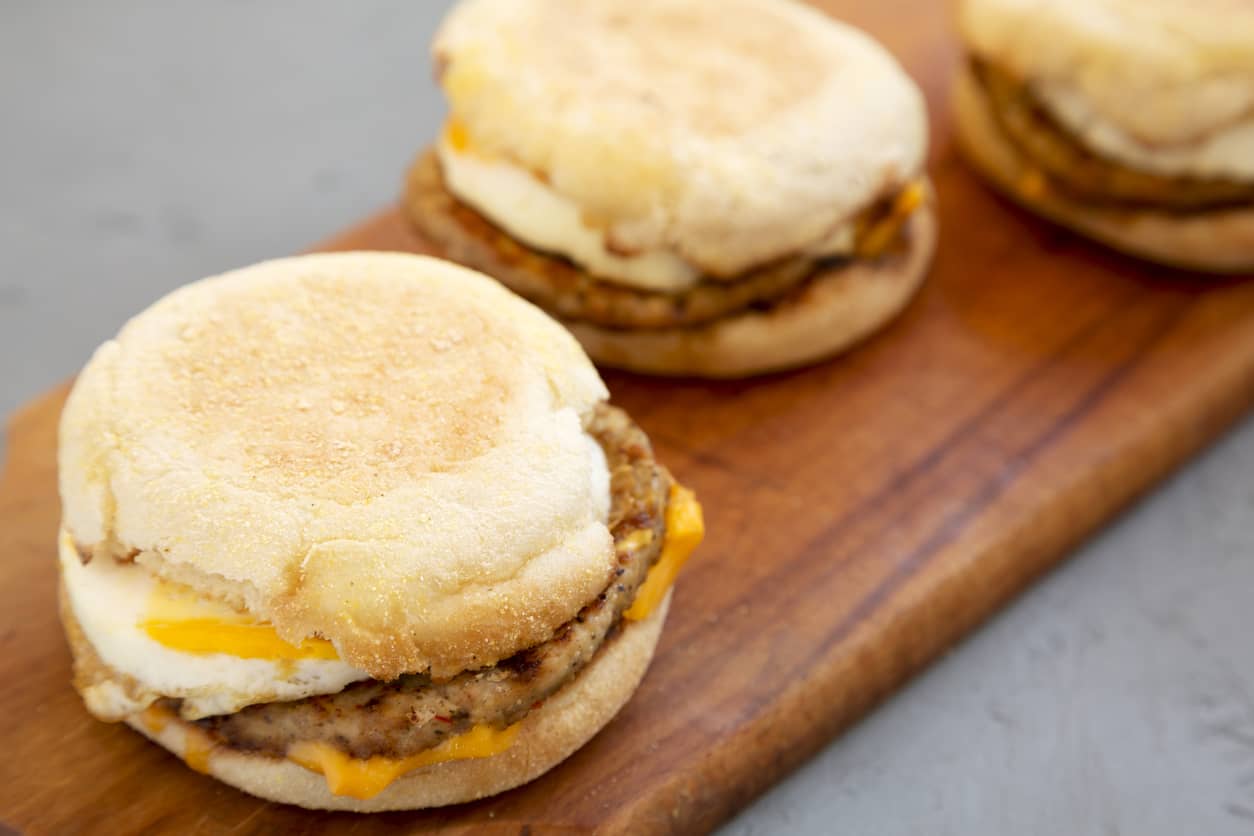 homemade-pork-roll-egg-sandwich-on-a-rustic-wooden-board-on-a-gray-surface-side-view-close-up