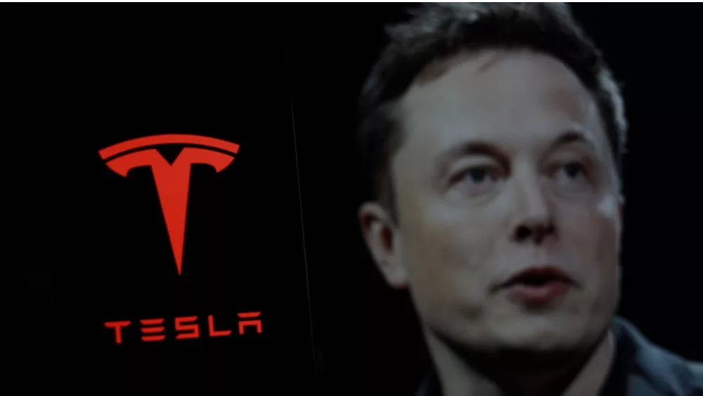 Tesla logo is displayed on smartphone screen With CEO Elon Musk in a background