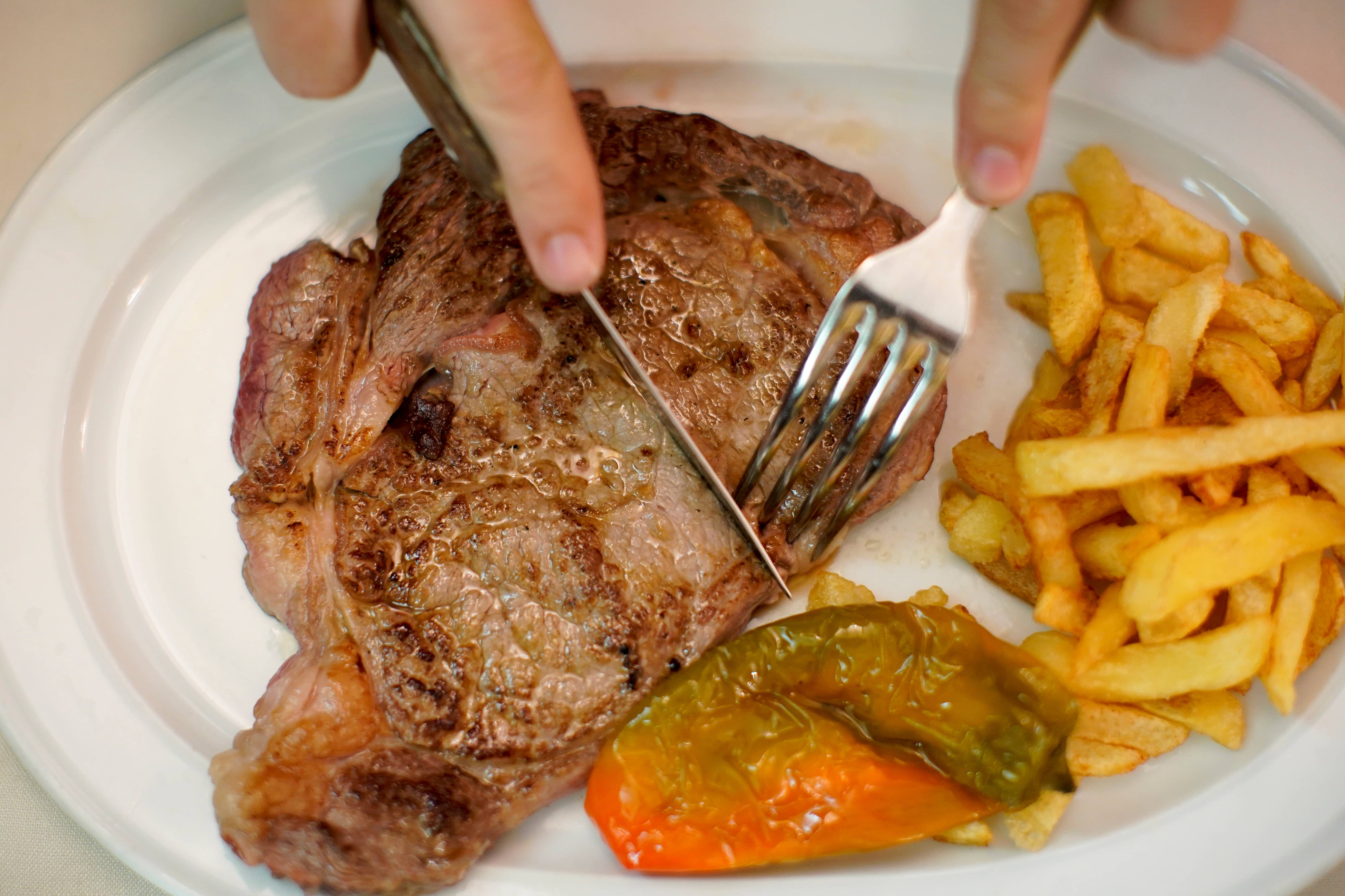 a-beef-steak-is-cut-at-the-taberna-del-gijon-restaurant-in-madrid