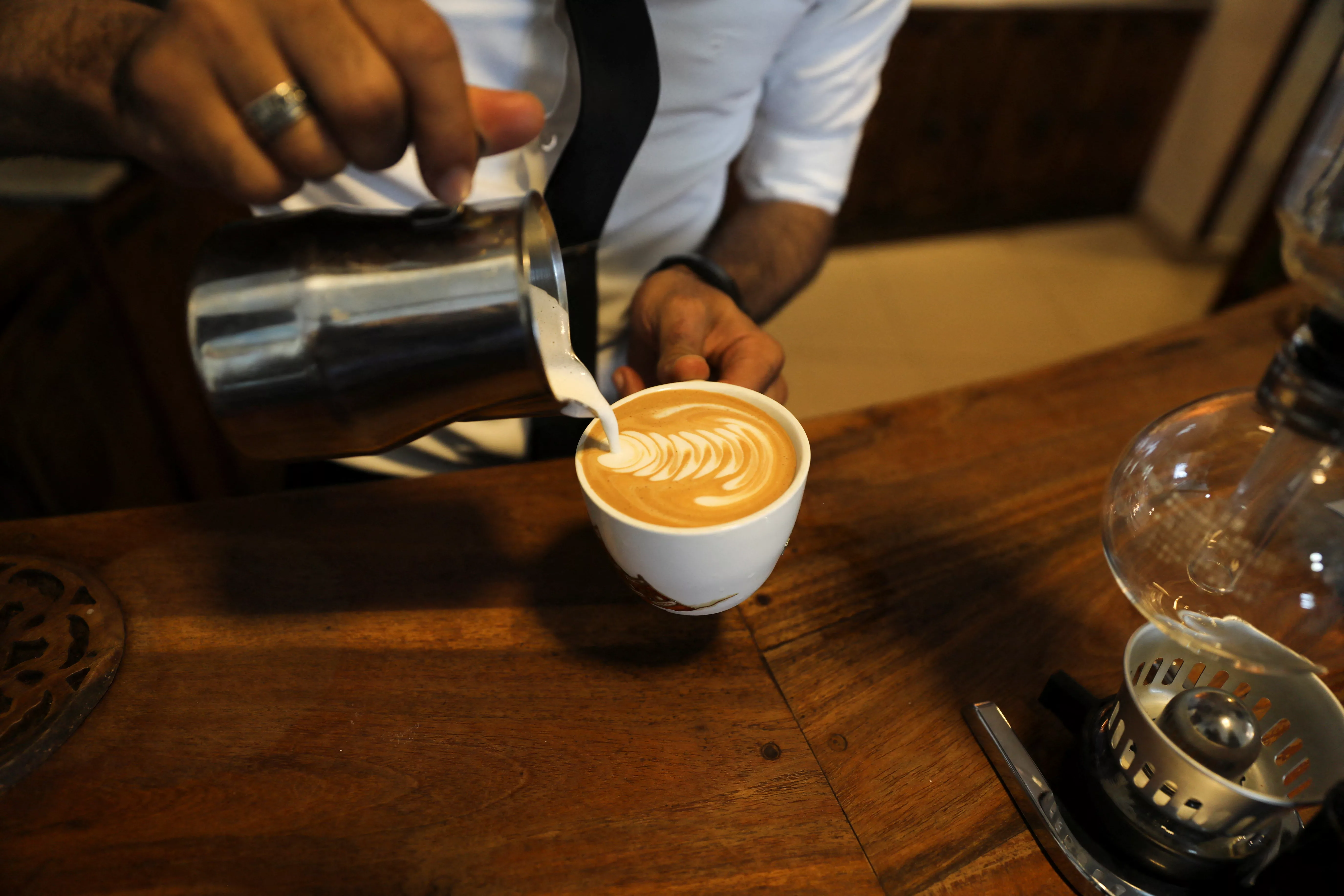 an-employee-pours-milk-into-a-cup-of-coffee-at-the-durar-specialty-coffee-store-in-sanaa