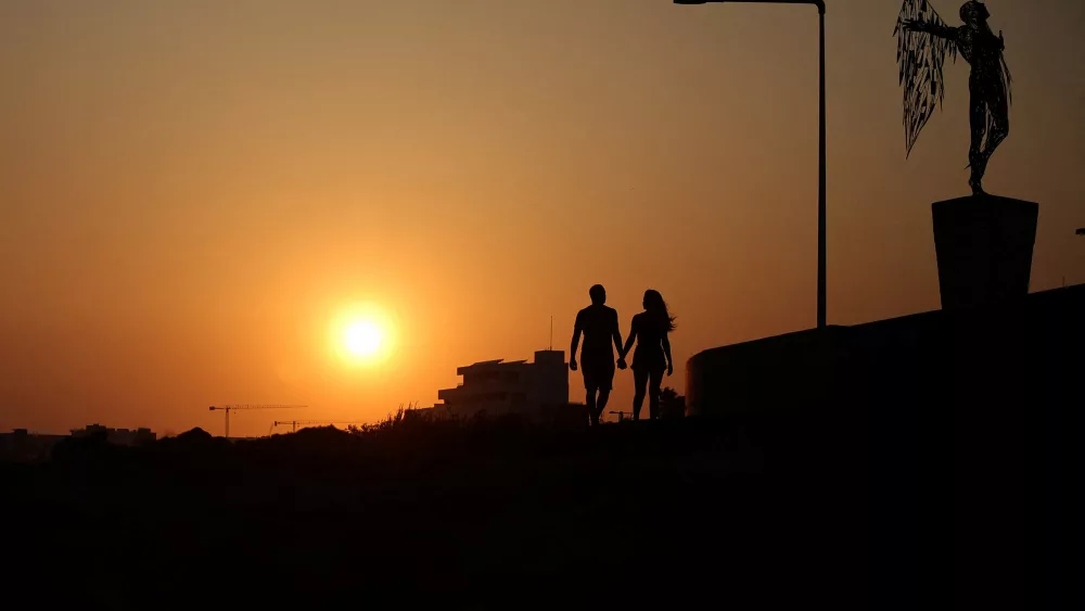 a-couple-walks-next-to-a-sculpture-during-sunset-in-ayia-napa