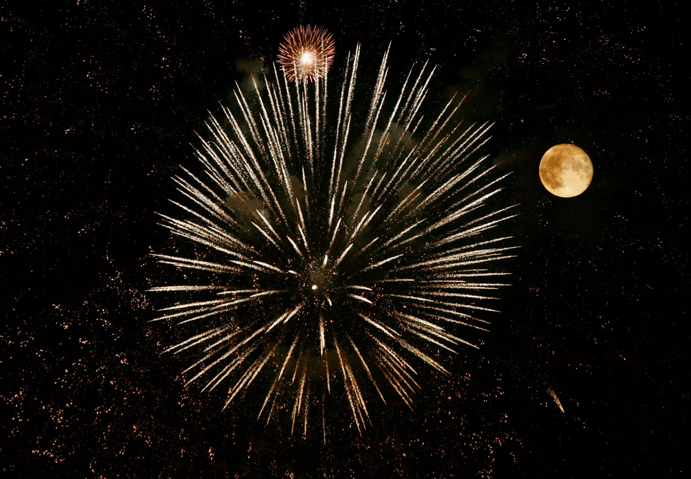 a-firework-explodes-next-to-a-full-moon-in-the-sky-over-berne