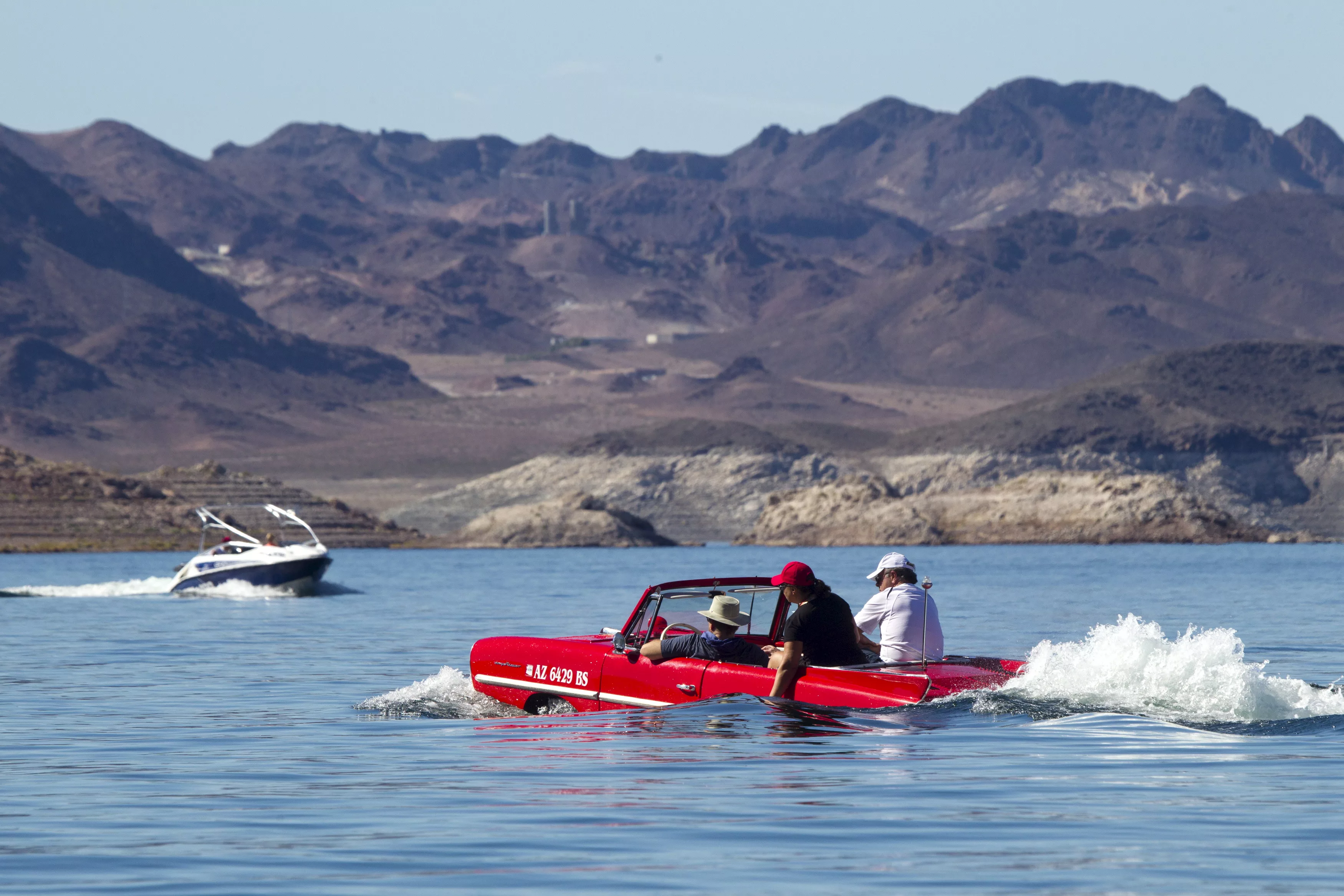a-speedboat-passes-by-a-1963-amphicar-driven-by-rob-vondracek-of-fountain-hills-arizona-during-the-first-las-vegas-amphicar-swim-in-at-lake-mead-near-las-vegas