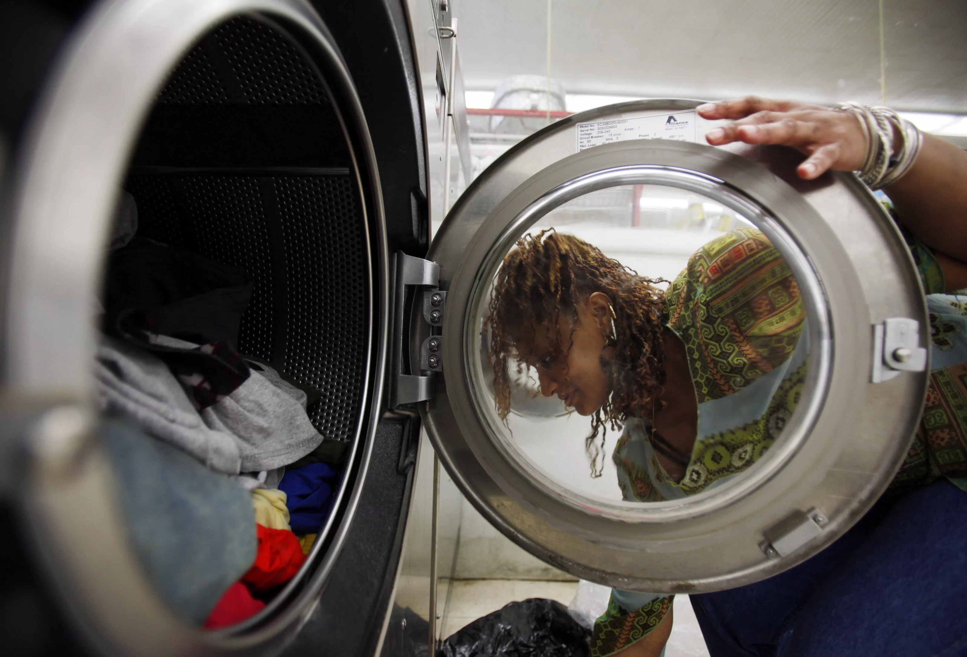 tarya-seagraves-quee-loads-laundry-into-the-washing-machine-at-a-laundromat-in-cambridge