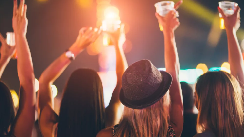 back-view-of-female-friends-drinking-beer-and-dancing-at-music-festival
