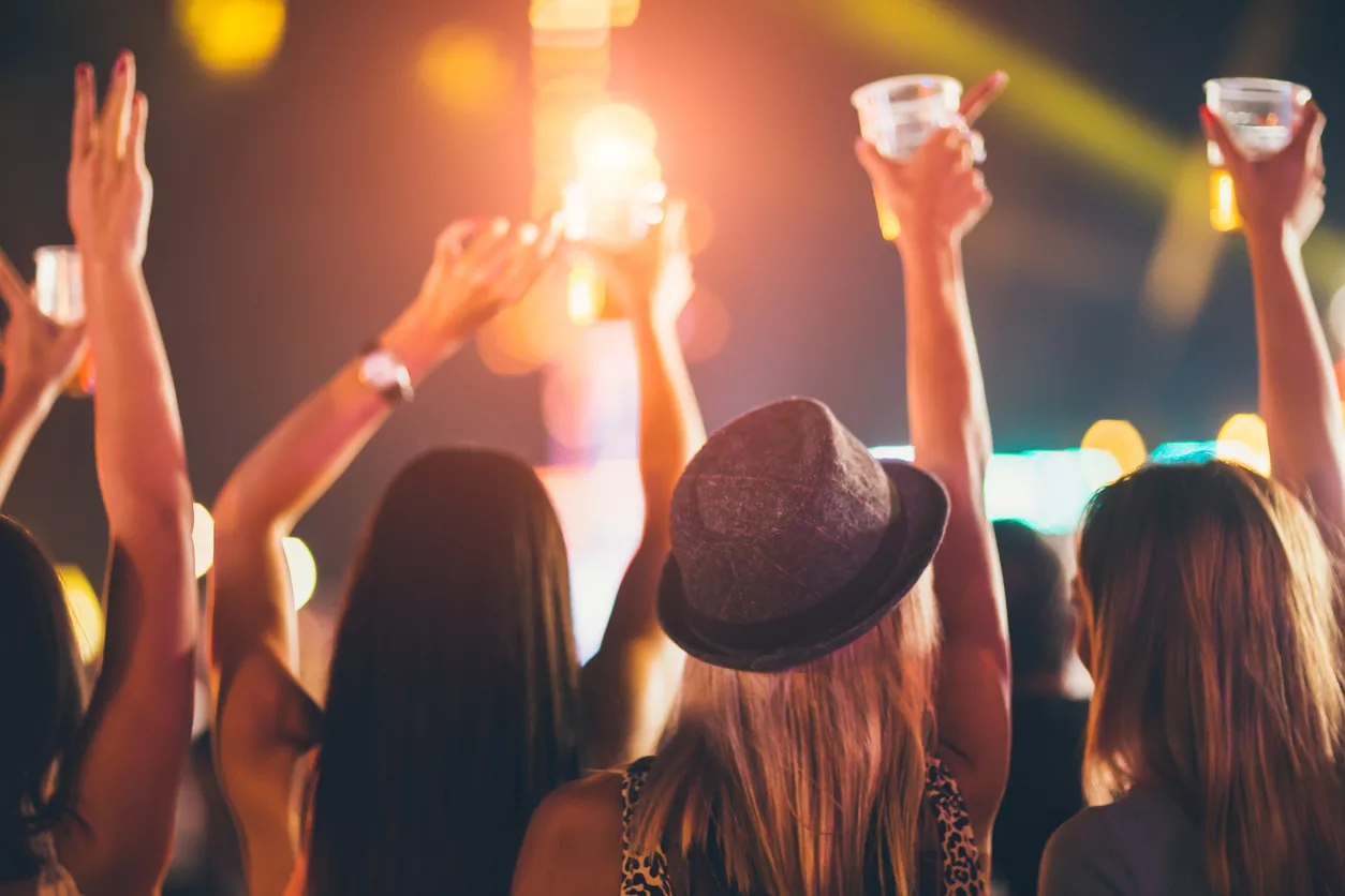 back-view-of-female-friends-drinking-beer-and-dancing-at-music-festival