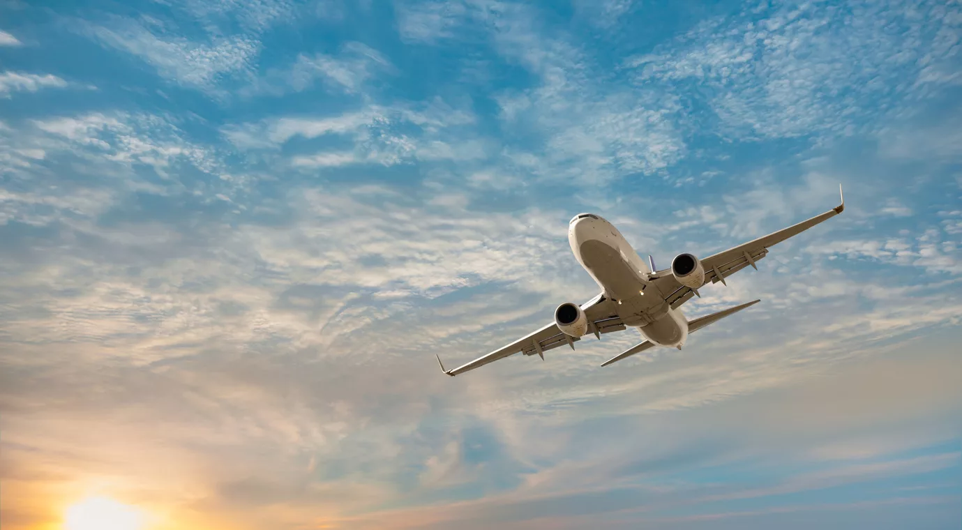 airplane-flying-over-tropical-sea-at-sunset