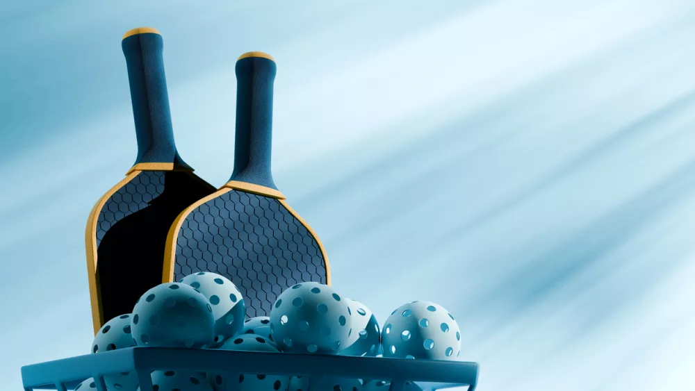 pickleball-sport-equipments-two-rackets-and-basket-of-balls-under-the-shadow-on-blue-background-3d-illustration-render-copy-space-hero-view