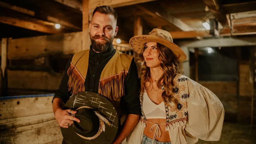 cowboy-and-cowgirl-with-hats-posing-at-rural-stable-at-ranch