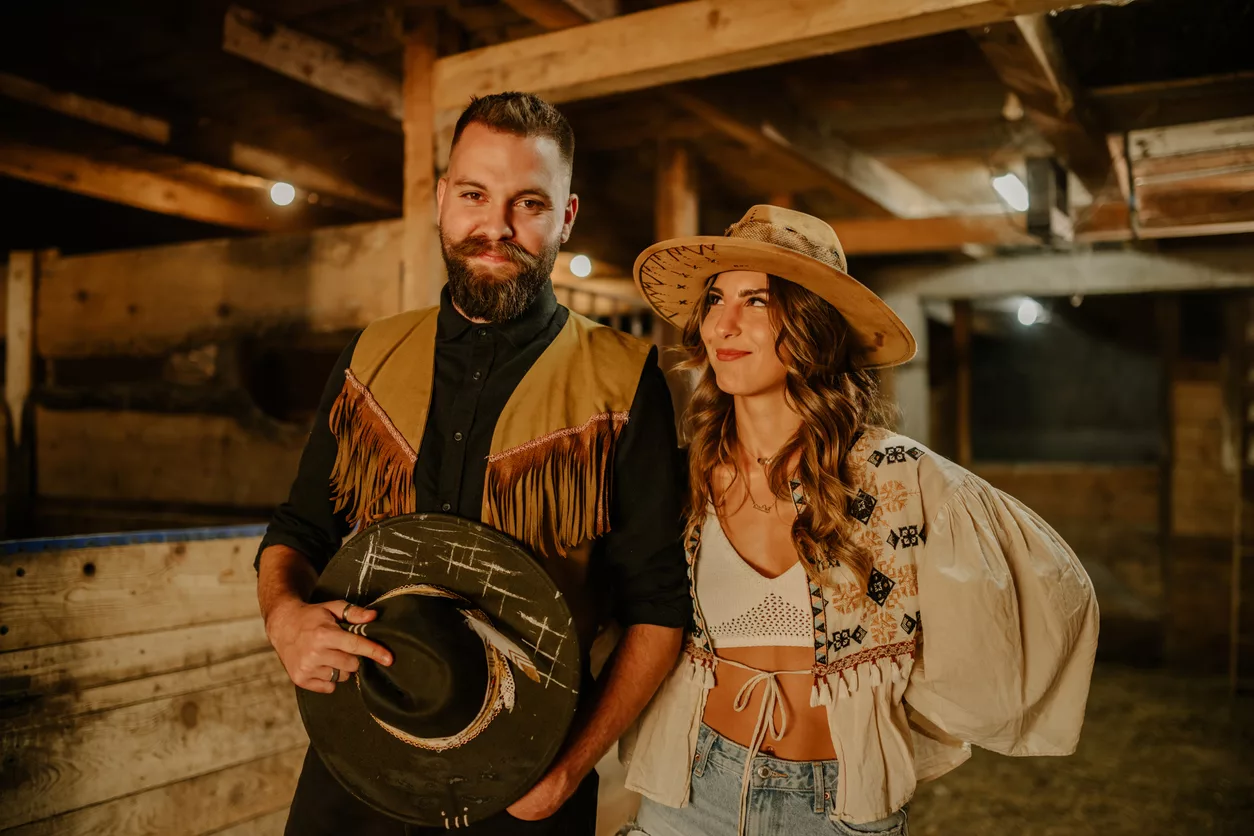 cowboy-and-cowgirl-with-hats-posing-at-rural-stable-at-ranch