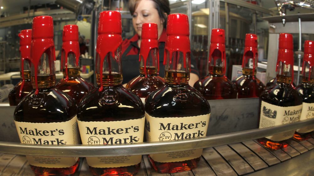 new-bottles-of-makers-mark-bourbon-on-the-conveyor-belt-pass-by-a-worker-after-being-hand-dipped-with-their-signature-red-wax-at-the-makers-mark-distillery-plant-in-loretto
