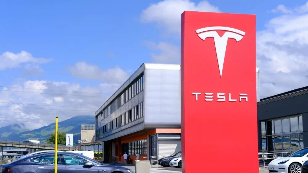 Tesla office^ American company^ electric car manufacturer Elon Musk^ company logo on red stand^ alternative energy development concept^ electric vehicle production^ Innsbruck^ Austria - June 2022