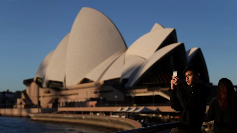 a-young-man-films-with-his-phone-in-front-of-the-sydney-opera-house-in-sydney