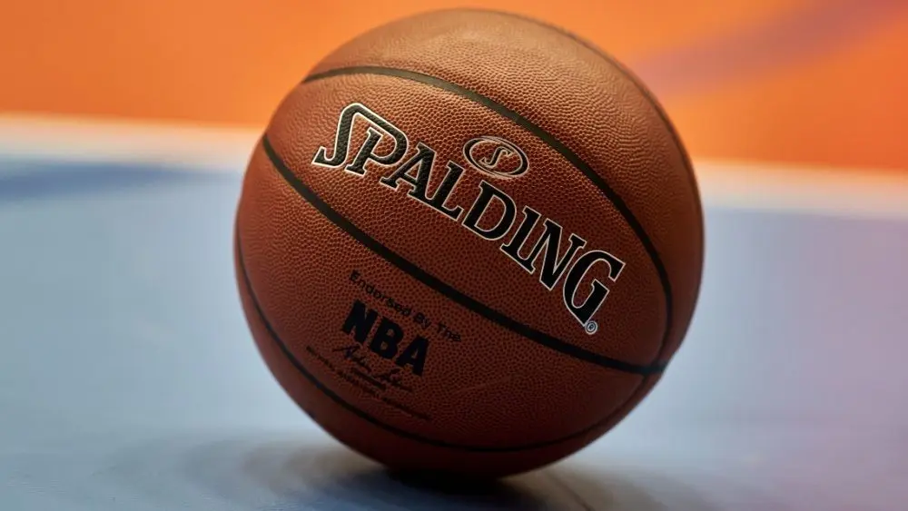 Gdansk^ Poland - 08 02 2024: Close-up of a Spalding NBA basketball resting on a blue and orange court^ focusing on the texture of the ball and the surrounding vibrant colors of the court.