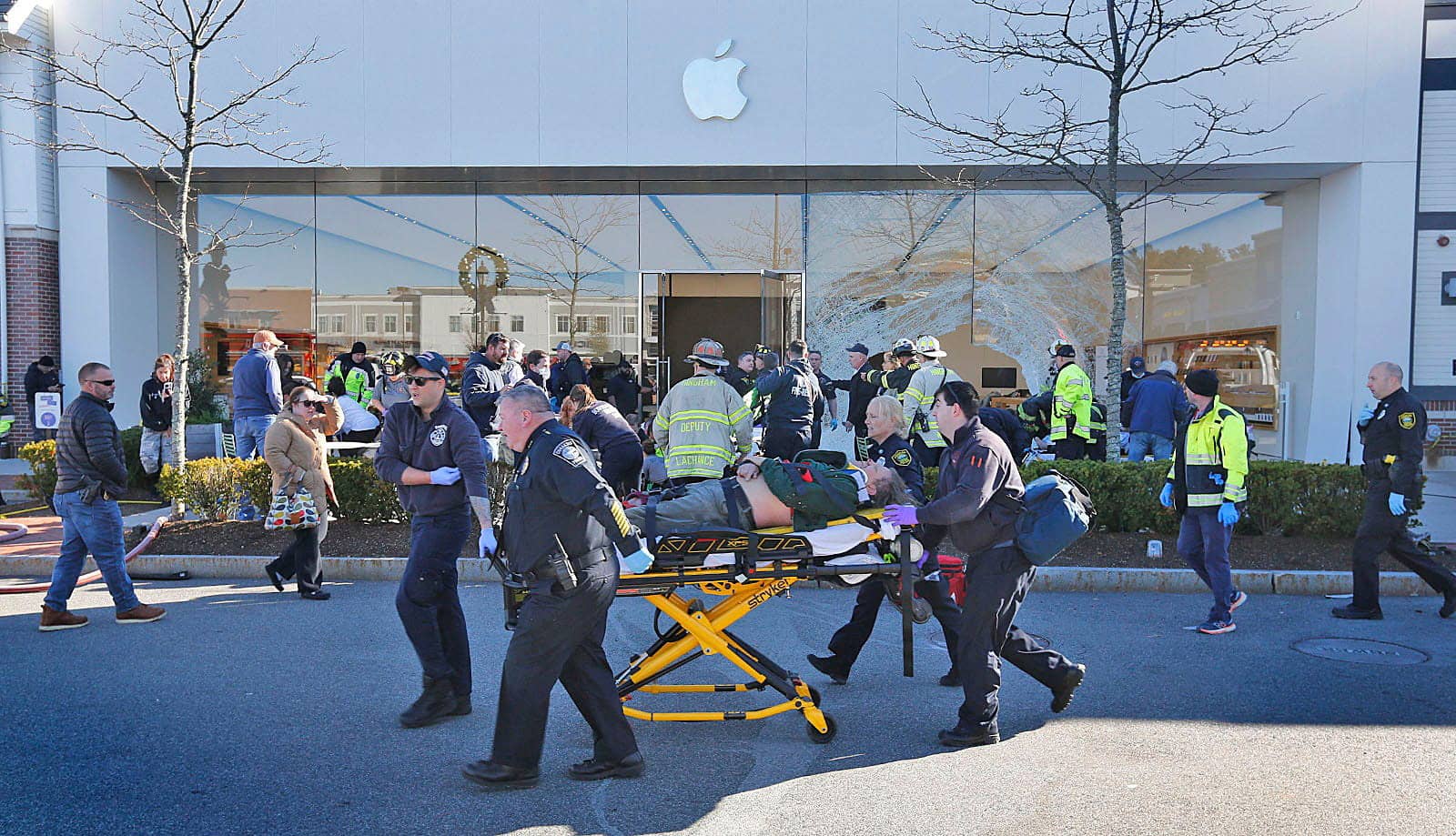 emergency-services-personnel-push-a-victim-to-a-waiting-ambulance-after-a-vehicle-crashed-into-an-apple-store