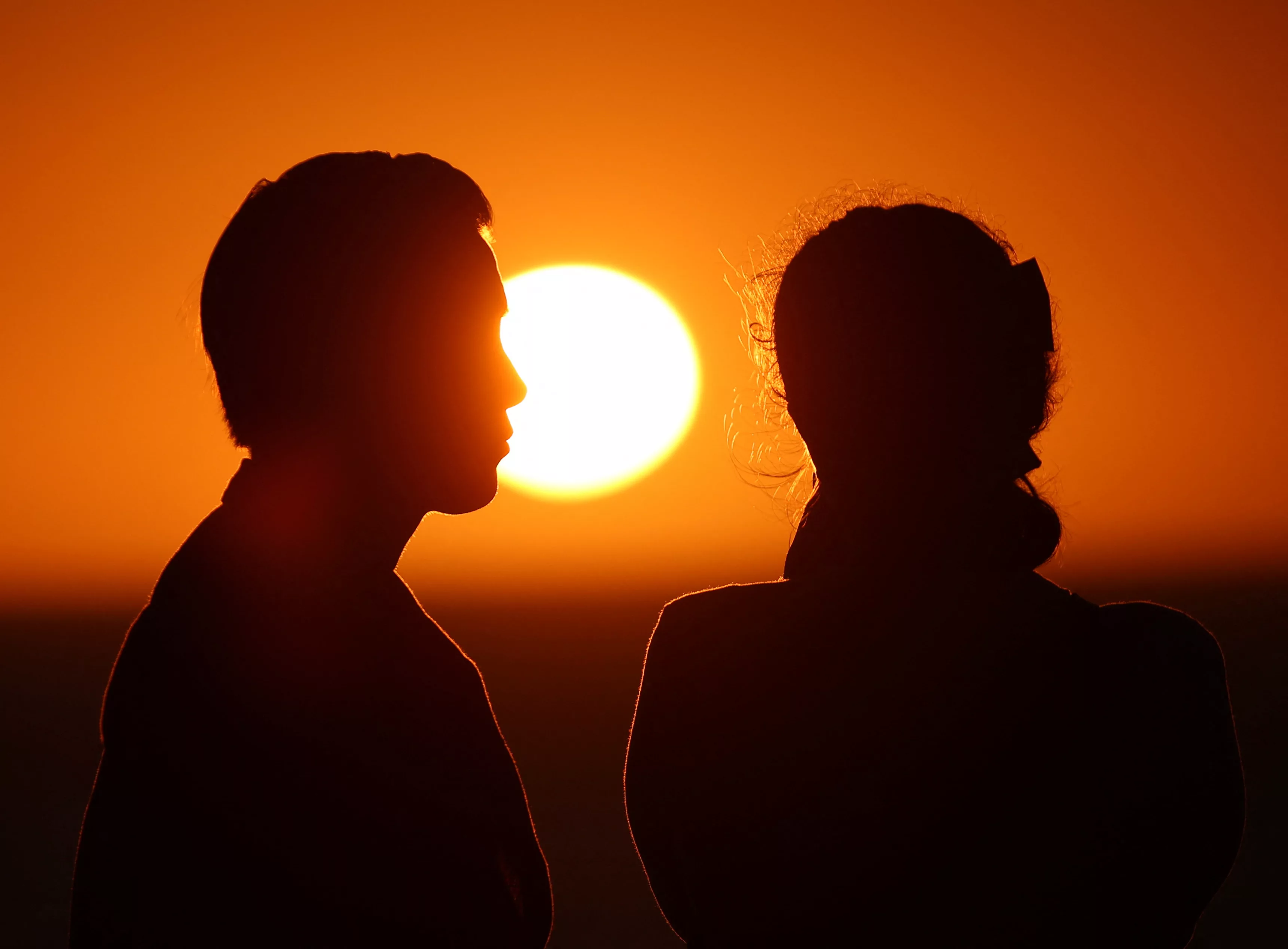 people-are-silhouetted-at-sunset-as-they-visit-the-malecon-one-day-ahead-of-a-total-solar-eclipse-in-mazatlan