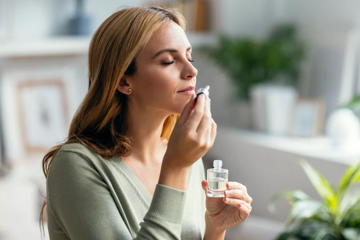 beautiful-woman-girl-holding-a-bottle-of-essential-oil-while-testing-it-sitting-on-a-couch-at-home