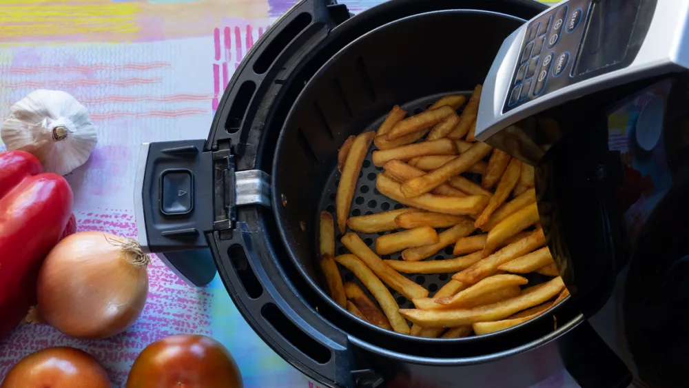 top-view-of-an-air-fryer-on-a-table-with-french-fries-and-vegetables