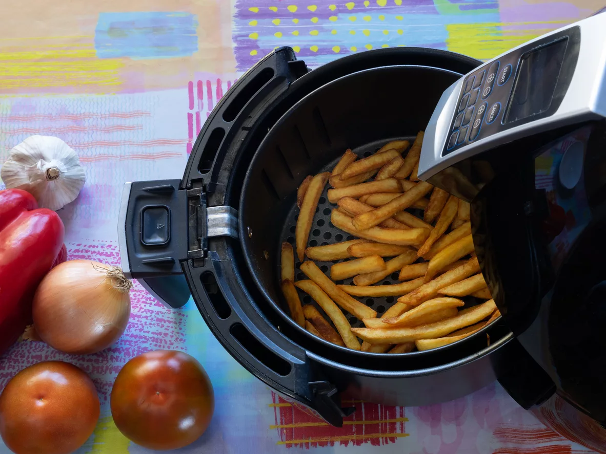 top-view-of-an-air-fryer-on-a-table-with-french-fries-and-vegetables