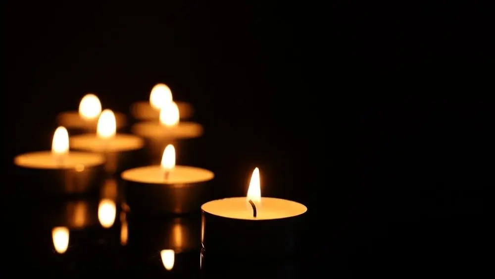 Burning candles on mirror surface in darkness^ closeup.