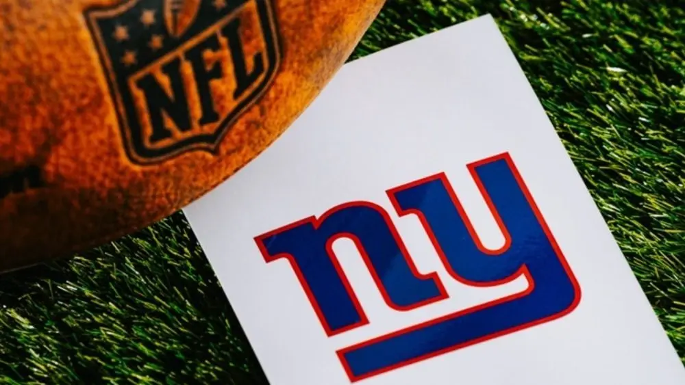 New York Giants NFL team Logo and American football ball on Green Grass. NEW YORK^ USA^ FEBRUARY 10^ 2025