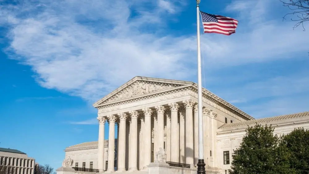 Facade of the United States Suprement Court with American flag in Washington^ DC
