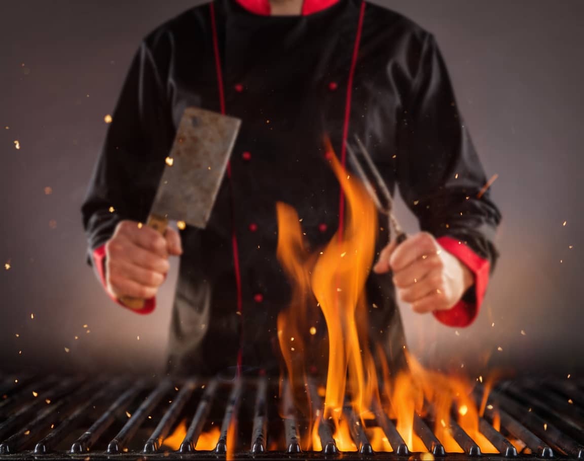 closeup-of-chef-holding-fork-above-the-grill