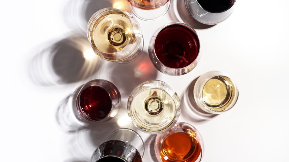 red-rose-and-white-wine-in-glasses-on-white-background-top-view-wine-bar-shop-winery-wine-tasting-concept-hard-light-and-harsh-shadows