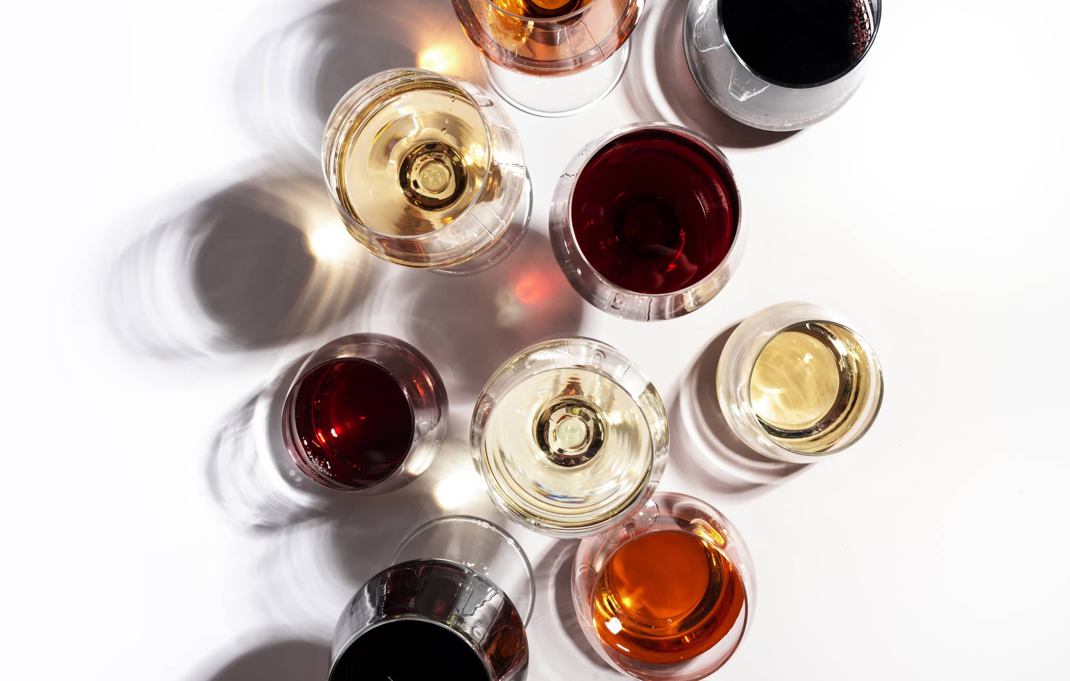 red-rose-and-white-wine-in-glasses-on-white-background-top-view-wine-bar-shop-winery-wine-tasting-concept-hard-light-and-harsh-shadows