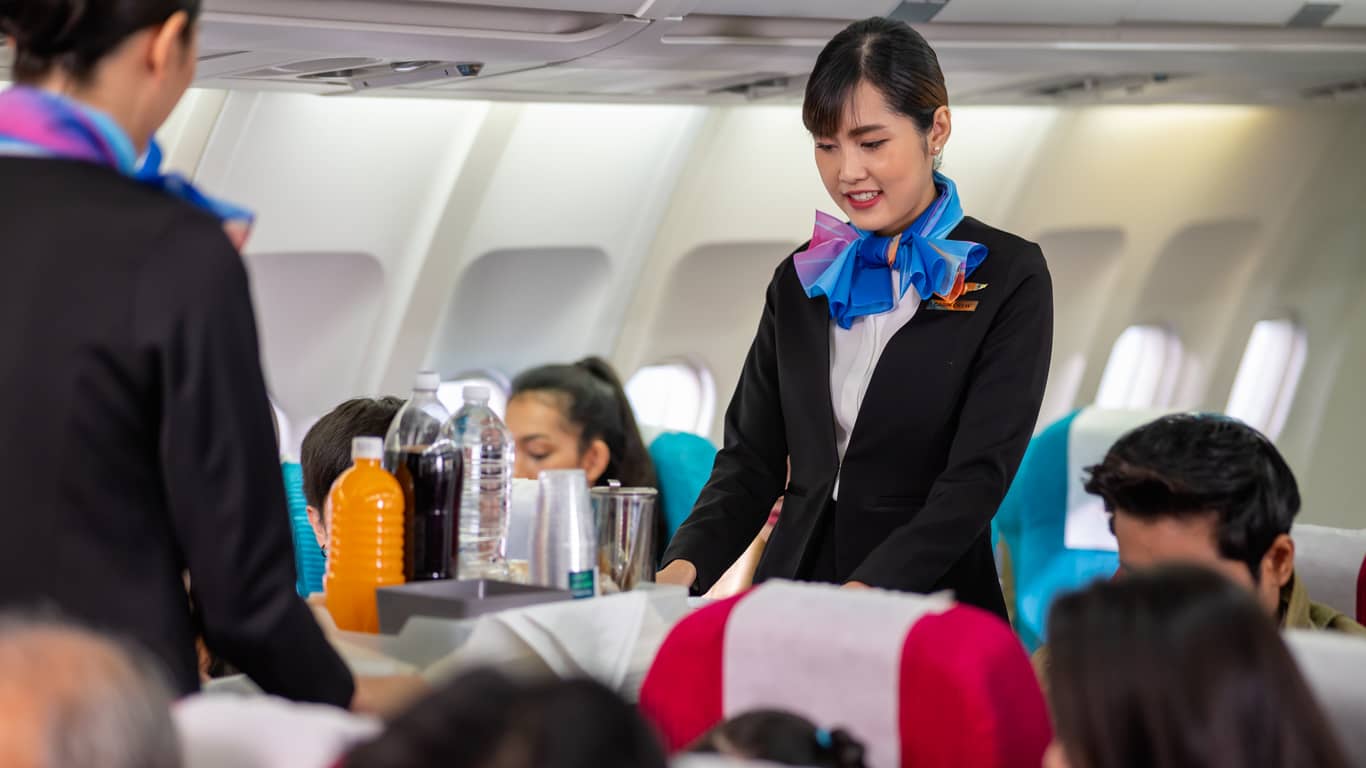 two-young-beautiful-asian-flight-attendant-serving-food-and-drink-to-passengers-on-airplane-two-stewardess-pushing-food-cart-along-aisle-to-serve-the-customer-airline-service-business-concept