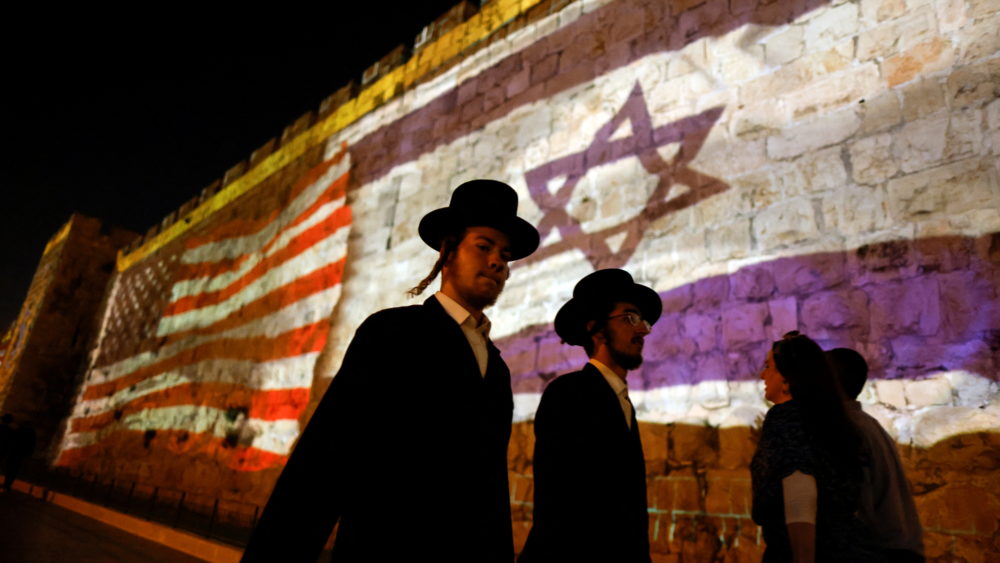 people-walk-by-as-the-u-s-and-israeli-national-flags-are-projected-on-a-part-of-the-walls-surrounding-jerusalems-old-city
