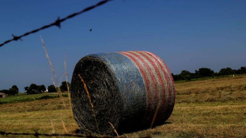 a-bale-of-hay-sits-wrapped-in-a-material-to-look-like-the-american-flag-on-a-farm-in-appleton-city-missouri