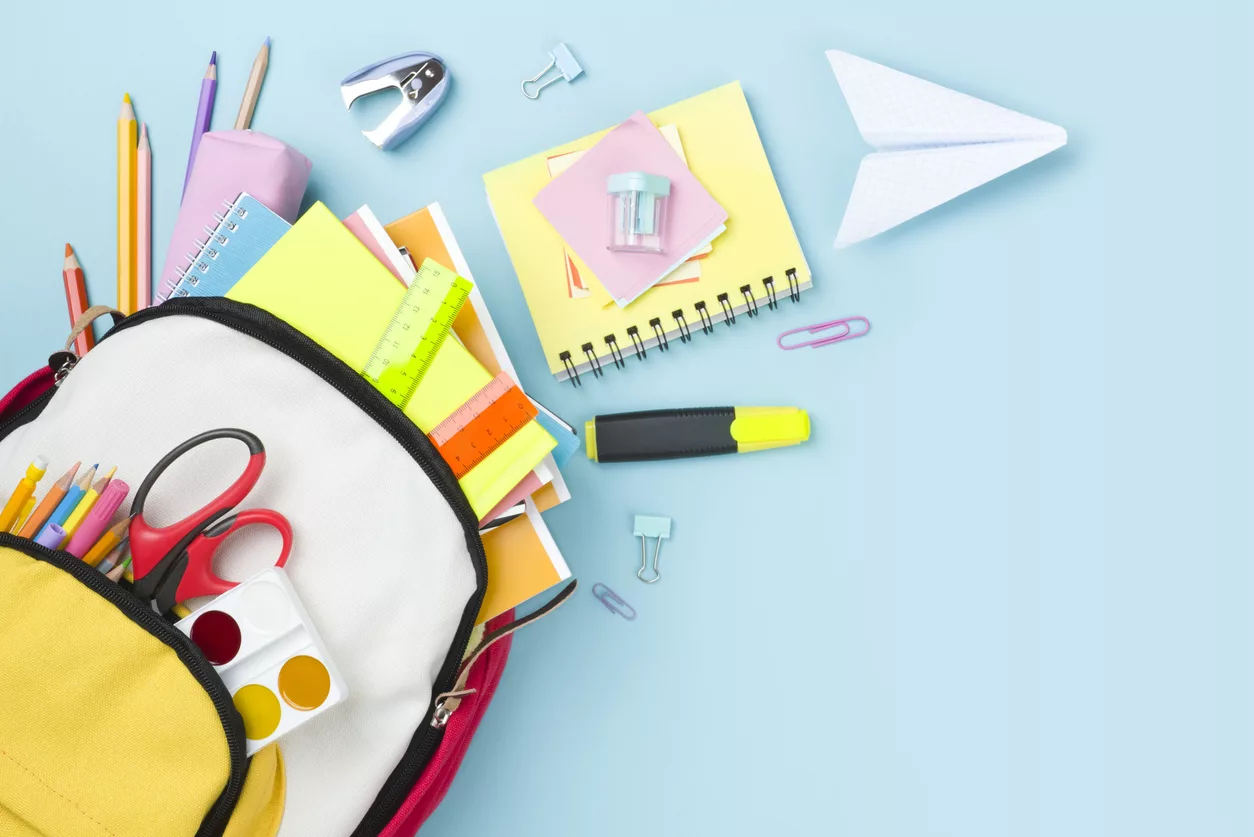 many-colorful-school-supplies-and-backpack-arranged-on-blue-background