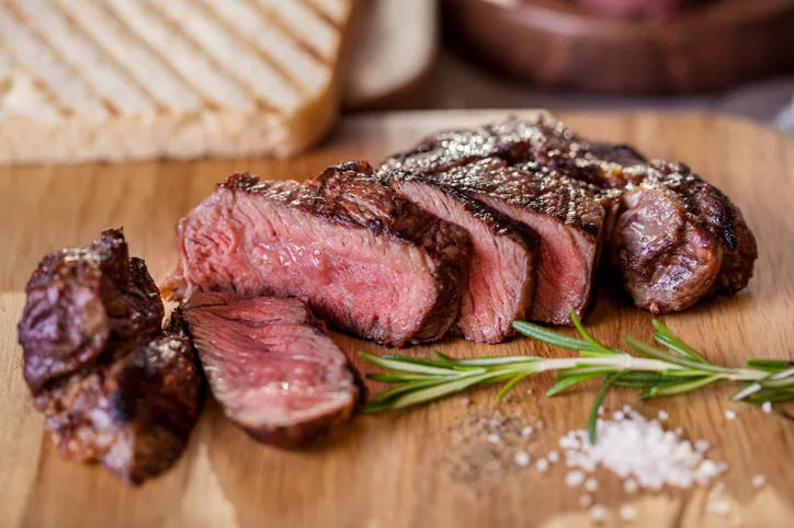 grilled-pork-steak-pieces-with-a-sprig-of-rosemary-pepper-and-salt-fried-pieces-of-bread-on-a-wooden-board-horizontal-orientation