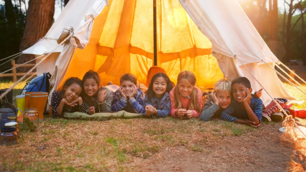 children-smiling-in-teepee-at-campsite