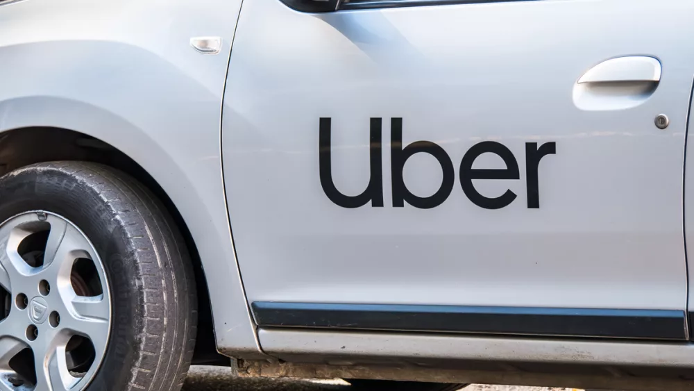 uber-logo-inscriptioned-on-a-white-painted-car-uber-car-in-traffic