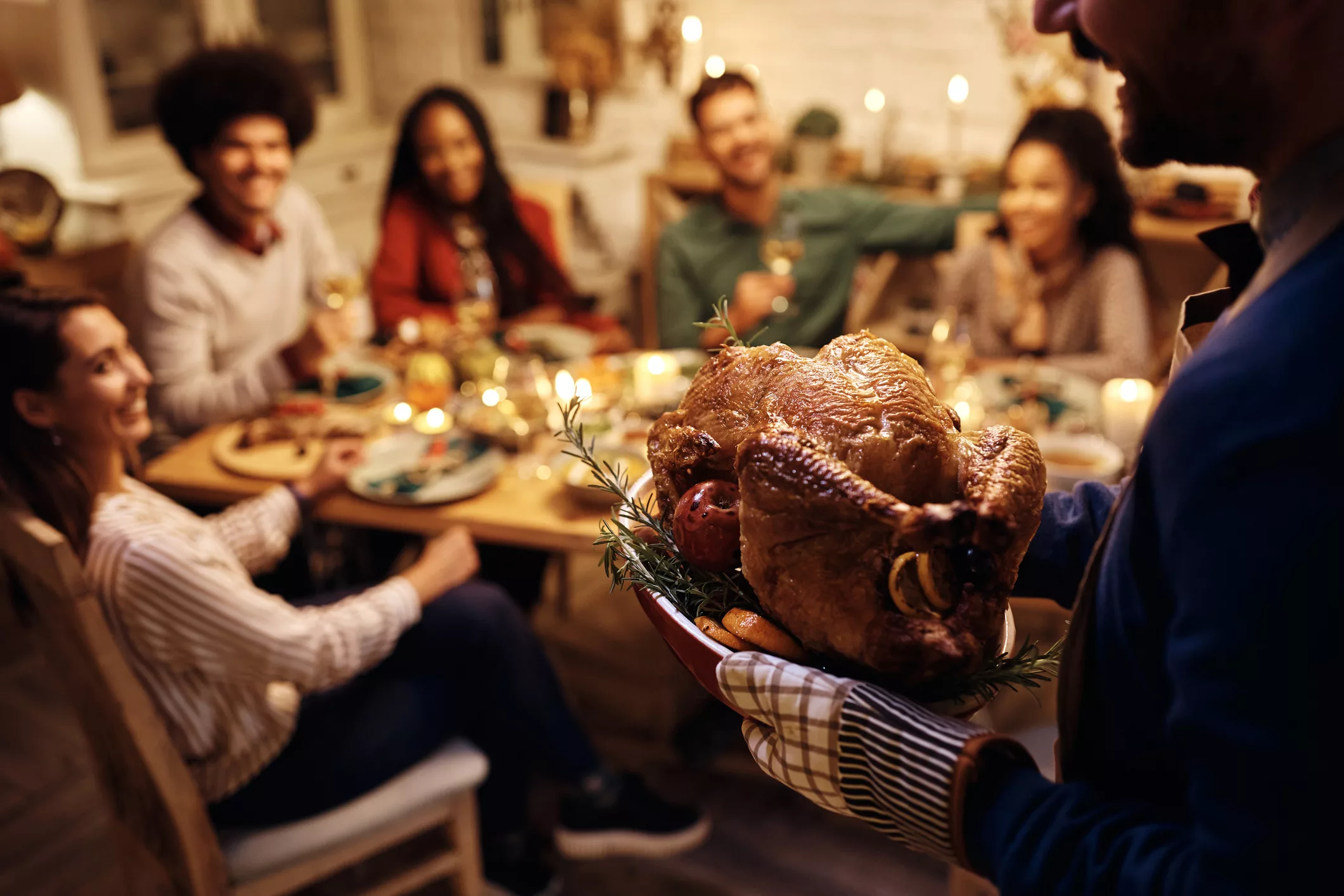 close-up-of-man-serving-roasted-turkey-during-thanksgiving-dinner-party-with-friend
