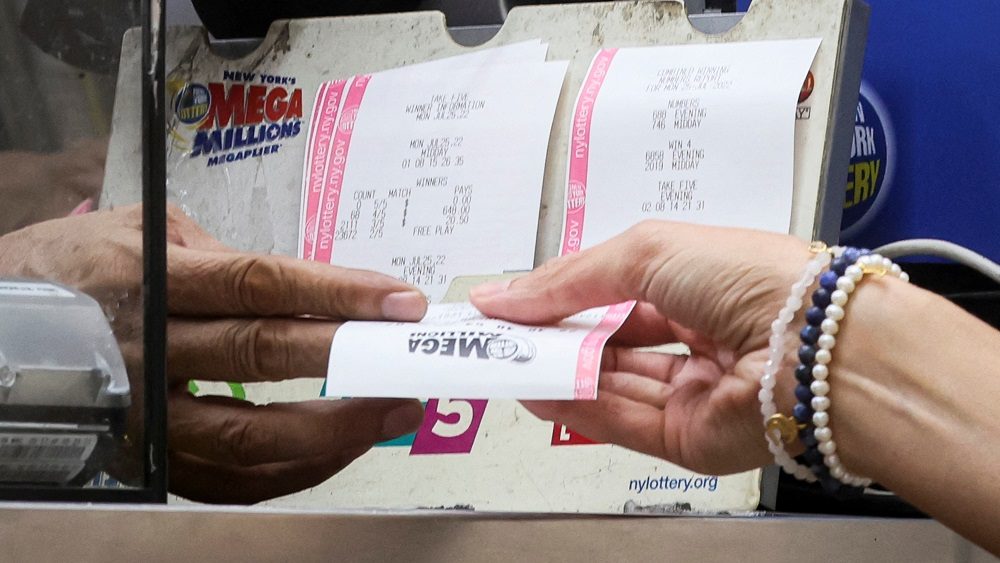 a-woman-buys-a-ticket-for-the-mega-millions-lottery-drawing-at-a-news-stand-in-new-york