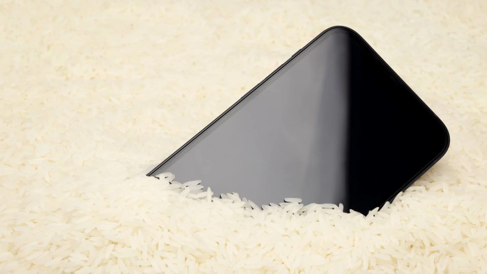 a-wet-smartphone-is-dried-in-raw-rice-on-white-background